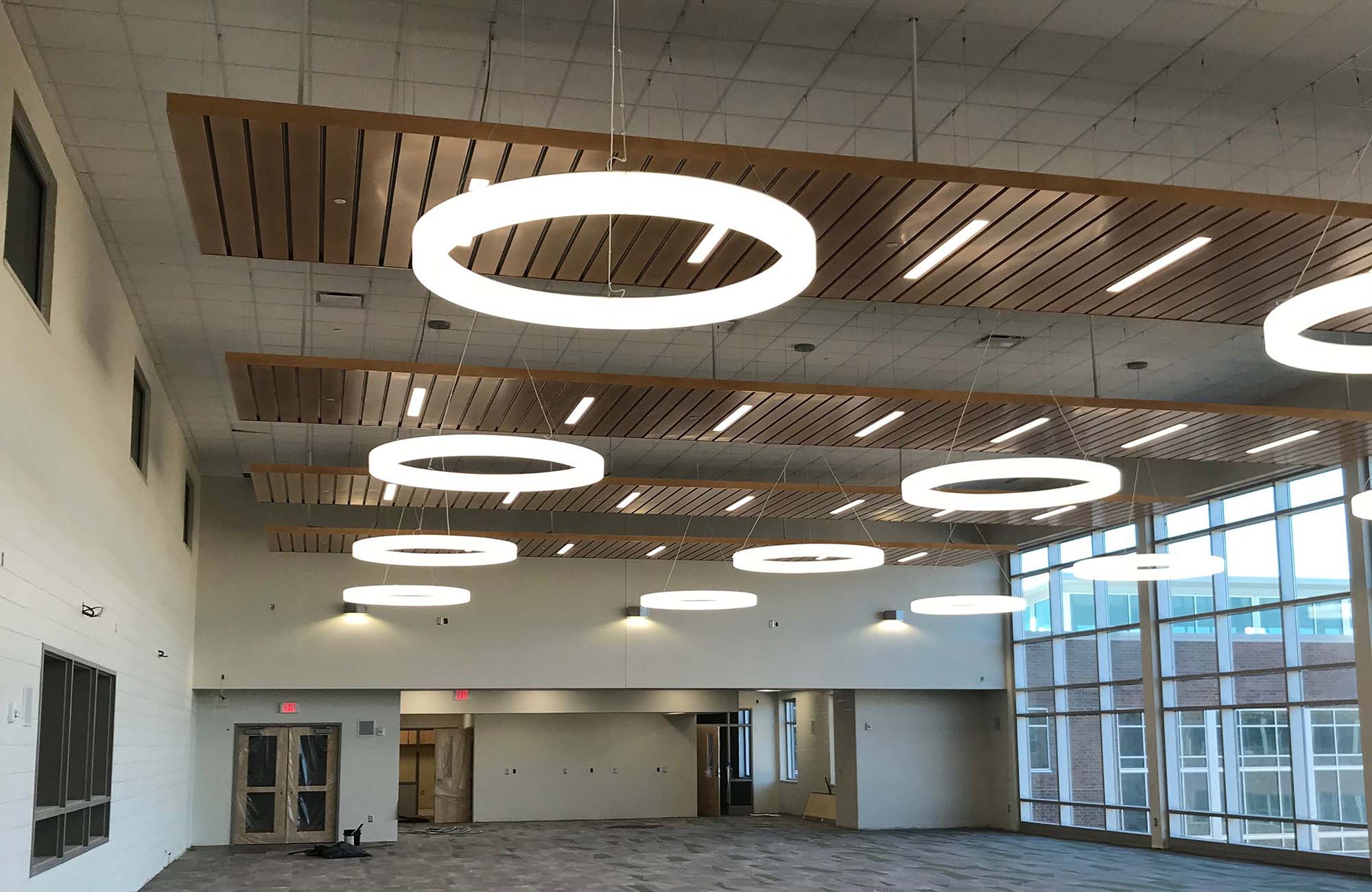 Recessed linear lighting and suspended ring lighting in a high school atrium